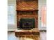 Close up view of a brick fireplace featuring a wood burning insert, tools and wood mantle at 1146 Crestmont Se Dr, Concord, NC 28025
