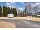 Spacious backyard with mature trees, featuring a storage shed and a gravel driveway at 11918 Crabapple Ln, Huntersville, NC 28078