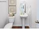 Stylish half bathroom featuring a pedestal sink, decorative mirror, and wooden floors at 1348 Secrest Commons Dr, Monroe, NC 28112