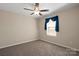 This bedroom features neutral walls, carpet, a ceiling fan and a window dressed with dark blue curtains at 147 Stanfield Farm Ln, Stanfield, NC 28163