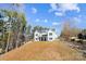 Elegant rear elevation of a house with a lawn on a hill and wooded areas in the background at 154 Fox Hunt Dr, Mooresville, NC 28117