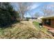 View of the grassy, fenced backyard with mature trees and a brick exterior on a sunny day at 2105 Monticello Dr, Gastonia, NC 28056