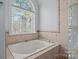 Bright bathroom featuring a soaking tub beneath a large window offering outdoor views and decorative tile at 214 Harbor Landing Dr, Mooresville, NC 28117