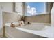 Relaxing bathroom features a soaking tub with a window view and travertine tile surround at 5006 Sand Trap Ct # 142, Monroe, NC 28112