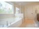 Bright bathroom featuring a soaking tub beneath a window and a glass enclosed shower at 5006 Sand Trap Ct # 142, Monroe, NC 28112