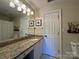 This bright bathroom features a granite counter and a wide mirror with lighting above at 6301 Royal Aberdeen Ct, Charlotte, NC 28277