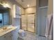 Bathroom showcasing a white vanity, toilet, enclosed shower with gold trim, and tile flooring at 8668 Coralbell Ln # 10, Charlotte, NC 28213