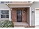 A close up of a front door, with brick surround, gray siding, and a cozy porch at 9014 Arbor Creek Dr, Charlotte, NC 28269