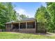 Backyard view of a brick house featuring a covered porch, dark railings, and green lawn at 11280 Mcfalls Dr, Fort Mill, SC 29707
