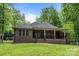 Brick home featuring a covered porch and green backyard, all surrounded by mature trees at 11280 Mcfalls Dr, Fort Mill, SC 29707