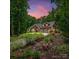 Beautiful stone and brick home with a three-car garage and lush landscaping under a vibrant evening sky at 11280 Mcfalls Dr, Indian Land, SC 29707