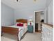 Cozy bedroom featuring light-blue walls, an inviting bed, a nightstand, and a glimpse of a hardwood-floored hallway at 150 Canopy Oak Ln, Statesville, NC 28625