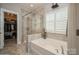 A bright bathroom featuring a tiled shower and separate soaking tub adjacent to the walk-in closet at 2112 Balting Glass Dr, Indian Trail, NC 28079
