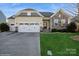 Inviting home with a well-maintained lawn, stone accents, and a two-car garage at 2112 Balting Glass Dr, Indian Trail, NC 28079