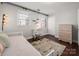 Bedroom featuring wood floors, two windows, a daybed, desk, a colorful area rug, and a chest of drawers at 4151 Ivystone Ct, Charlotte, NC 28277