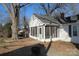 Exterior shot of this home's screen porch, brick border, mature trees, and inviting facade at 802 Lewis St, Gastonia, NC 28054