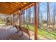 Covered patio with brick flooring and a bench overlooks a landscaped backyard with mature trees at 8802 Glenside St, Huntersville, NC 28078