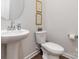 Neat powder room with a pedestal sink and toilet featuring a round mirror and neutral colors at 920 Clementine Rd, Monroe, NC 28110