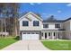 Townhome features gray siding, black shutters, a stone foundation, a driveway, and grass at 1608 Breezewood Dr, Charlotte, NC 28262