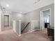 Upstairs hallway with neutral carpet and paint leading to doorways and a stairwell at 1630 Sassafras Ct, Fort Mill, SC 29715