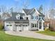 Charming two-story home boasts a three-car garage, inviting front porch, and well-manicured lawn at 2127 Nims Village Dr, Fort Mill, SC 29715