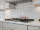 Close-up of modern stovetop with stylish white backsplash and countertops in the spacious kitchen at 2127 Nims Village Dr, Fort Mill, SC 29715