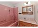 Pink bathroom boasts vanity with storage, matching tub/shower, and a mounted medicine cabinet at 2274 Old Wilkesboro Rd, Statesville, NC 28625