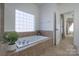 Corner soaking tub with tile surround, a decorative window, and a plant on the side at 228 Black Mountain Dr, Fort Mill, SC 29708