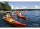 People kayaking on lake in orange kayaks enjoying water activity near tree lined shore at 4399 Reed Creek Dr, Sherrills Ford, NC 28673