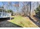 View of the backyard features a wooden porch and a lawn with a border of bare trees and foliage at 4607 Carmel Vista Ln, Charlotte, NC 28226