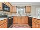 Traditional kitchen with wood cabinets, black appliances, and a bright window over the sink at 4607 Carmel Vista Ln, Charlotte, NC 28226