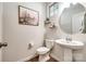 Well-lit powder room featuring a pedestal sink, round mirror, and decorative shelving at 5212 Spanish Ivy Ln, Indian Land, SC 29707