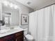 A clean and simple bathroom featuring a vanity with a sink, toilet, and a shower with a curtain at 6449 Silver Star Ln, Charlotte, NC 28210