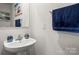 Cozy bathroom with pedestal sink, decorative mirror, and beach-themed wall decor at 668 Pointe Andrews Sw Dr # 93, Concord, NC 28025