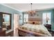Serene main bedroom featuring light blue walls, chandelier, and luxurious king-size bed at 7035 Walnut Branch Ln, Charlotte, NC 28277