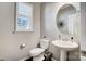 Modern powder room featuring a pedestal sink, round mirror, plantation shutters and neutral paint at 7035 Walnut Branch Ln, Charlotte, NC 28277