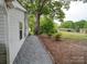 Landscaped side yard view with trees and a glimpse of a neighboring house in a peaceful setting at 709 High St, Albemarle, NC 28001