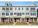 Row of three-story townhomes featuring gray siding, black shutters, and brick accents beneath a clear blue sky at 7113 Brookview Ln, Sherrills Ford, NC 28673