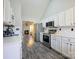 Modern kitchen with white cabinets, stainless steel appliances, and view into the living room with fireplace at 7220 Hidden Creek Dr, Charlotte, NC 28214