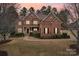 Charming brick home exterior with manicured lawn, landscaping, and beautiful sunset at 16506 Doves Canyon Ln, Charlotte, NC 28278