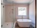 Modern bathroom featuring a freestanding tub, glass shower with tile and a bright window at 240 Mark Ryan Ln, Dallas, NC 28034
