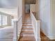 Bright hallway featuring a modern chandelier, hardwood floors, staircase, and decorative wall molding at 240 Mark Ryan Ln, Dallas, NC 28034