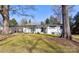 Charming single-story home with a white brick facade, a covered carport and mature trees shading the front yard at 435 Caldwell Se Dr, Concord, NC 28025