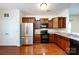 Well-equipped kitchen boasting wooden cabinetry, stainless steel refrigerator, and sleek black appliances and hardwood floors at 5216 Crystal Lakes Dr, Rock Hill, SC 29732