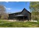 Exterior view of a black modern home featuring a stone base and an outdoor patio at 1575 Shinnville Rd, Cleveland, NC 27013