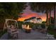 Inviting backyard space with a fire pit, swing, and view of the elegant home under a colorful sunset at 2477 Peninsula Shores Ct, Denver, NC 28037