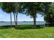 Expansive backyard leading to the serene lakefront, showcasing lush greenery and mature shade trees at 2477 Peninsula Shores Ct, Denver, NC 28037