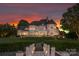 Elegant two-story home with a beautifully landscaped yard, inviting porch, and sunset sky at 2477 Peninsula Shores Ct, Denver, NC 28037