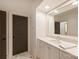 Well-lit bathroom with a large mirror, vanity, and tiled floors; dark door leading to another room at 2544 Portland Ave, Charlotte, NC 28207