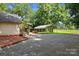 Home's backyard with ample parking, covered area, brick fireplace, and manicured landscaping at 28419 Nc Hwy 73 Hwy, Albemarle, NC 28001